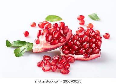 Two Pieces Of Delicious Young Ripe Pomegranate, A Pile Of Pomegranate Seeds And Beautiful Young Pomegranate Leaves With A Shadow On A White Background