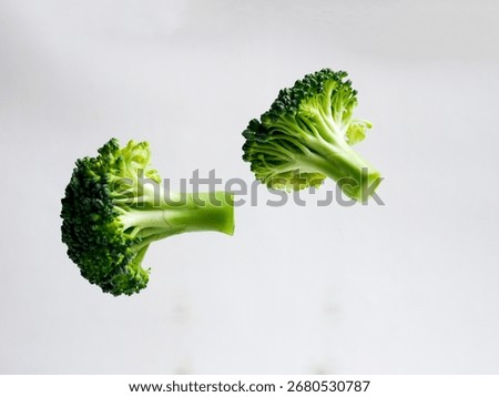 two pieces of flying broccoli vegetable, on a white background, isolated.