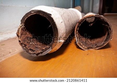 Two pieces of an old sewer pipe. Apartment in a multi-storey residential building in the city. Heavy pollution. Horizontal frame. Soft focus.