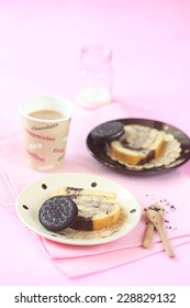 Two Pieces Of Oreo Swiss Roll Cake On Two Plates, Little Wooden Spoons And Glass Of Coffee, On Light Pink Background.
