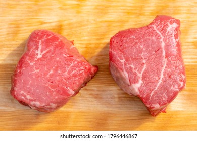 Two Pieces Of Raw Beef Tenderloin Steaks On A Maple Wood Cutting Board