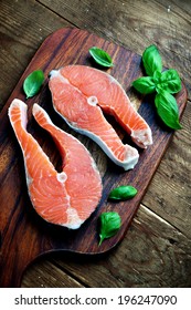 Two pieces of red salmon fillets placed on the wooden cutting board