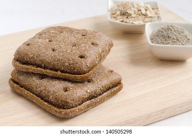 Two Pieces Of Rye Bread Square Shape, Bran And Muesli Isolated On Wooden Background