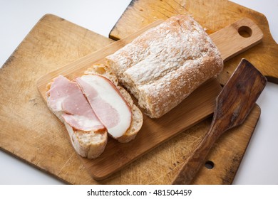 two pieces of white bread with two pieces of bacon on a wooden Board