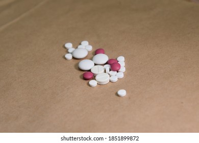 Two Piles Of Pills And Pills On A Brown Background Symbolize The Choice Between A Large And Small Dose Of Medication