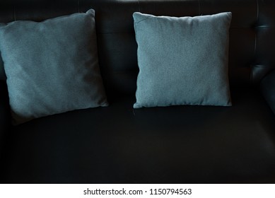 Two pillows and empty black leather sofa background.Furniture decoration in the reception room.