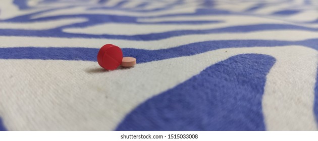 Two Pills Lying On A Bedsheet, Captured At An Angle.