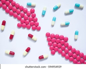 Two Pink Arrows Made By Pink Pills With Different Medicine Capsules On Blue Tone Background. Creative Idea For Drug Comparisons, Drug Interaction, Side Effect And Pharmacy Development Concept.