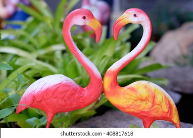 Two pink ceramic Flamingo in love and making a heart shape - Powered by Shutterstock