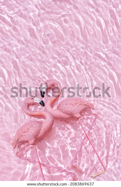 Two pink flamingos forming a heart in water pink background. Valentine's day concept 