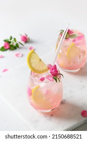 Two Pink Rose Beverage Or Lemonade, Cocktail With Rose Flowers And Lemon On White Sunny Background. Close Up. Vertical Format.