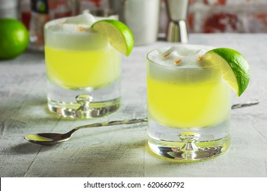 Two Pisco Sour Cocktails In Glasses With A Lime And Ingredients On The Bar