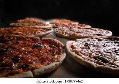 
two pizzas on a table on a dark background