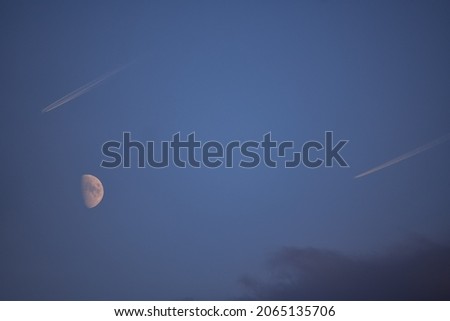 Two planes flying in the blue sky in parallel. Domestic transport aircraft around the crescent moon