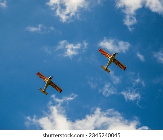 two planes in synchronized flight with a blue cloudy sky in the background