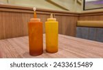 Two plastic bottles filled with various types of sauce at solaria restaurant. chily and tomatoe sauces.