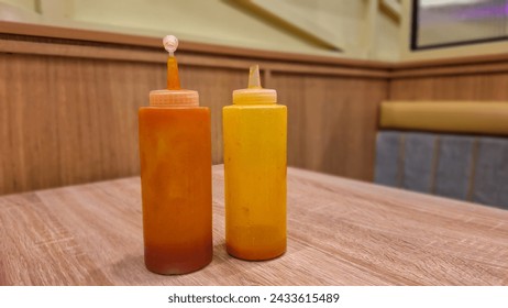 Two plastic bottles filled with various types of sauce at solaria restaurant. chily and tomatoe sauces.