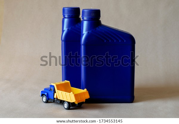 Two plastic canisters with car oils and a toy\
dump truck. Plastic containers for automotive lubricants. Car\
service. Automotive chemistry. Selective focus.Plastic containers\
for automotive lubricants