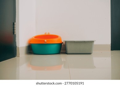 Two plastic containers sitting on shiny tiled floor next to wall