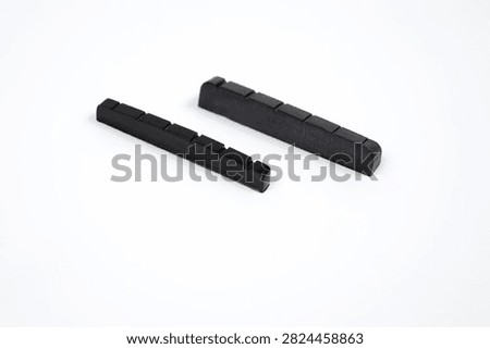 Two plastic guitar nuts, shot in close-up against a white background.