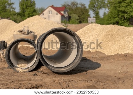Two plastic pipes with a corrugated surface lying on a construction site. A large road construction site, construction elements (sewage system!?) lying on the ground against the background of gravel. 