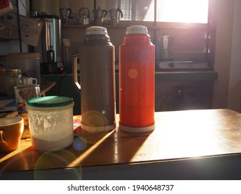 Two Plastic Thermos Flasks On Table In The Kitchen, Thermos Flask And Non-dairy Creamer Bottle, Morning Time, Transmittance Of Light, Mocca Pot Son The Wall, Sun Light