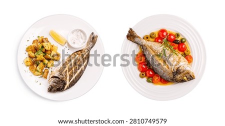 Two plates of sea bream fish prepared with golden potatoes and fresh vegetables, isolated on white