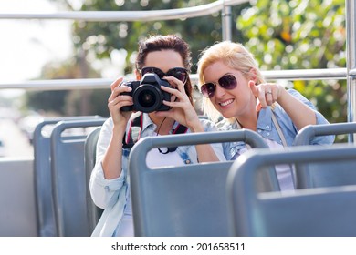 two playful tourists taking fun photos from an open top bus while touring the city