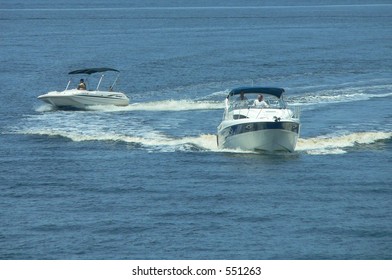 Two Pleasure Boats Crossing Paths On A Calm Blue Body Of Water. Example Of Potential Boating Accident On Waterway, Or Recreational Boating Intersection. Horizontal Image Has Copy Space In The Water.