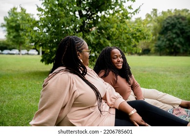 Two Plus Size Black Friends Sitting Down Hanging Out At The Park