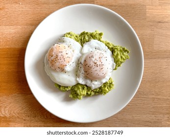 Two poached eggs on smashed avocado on a small round white plate