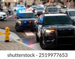 Two police cars with emergency lights on stopped in urban traffic 