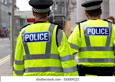 Two police officers in hi-visibility jacket patrolling in the city. British Police officers