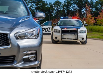 Two Police Vehicles Stop A Sedan On A Routine Traffic Stop