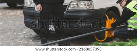 Two policeman setting a wheel clamp on a wrong parked car
