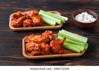 Two Portions Of Buffalo Wings With Fresh Celery Stalks And Blue Cheese Dip