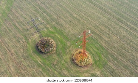 Two Power Line Tower In Autumn Field From Birds Eye View. Photo From The Drone.