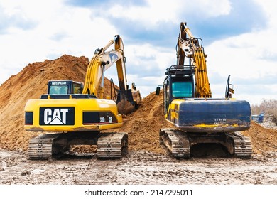 Two powerful excavators work at the same time on a construction site, sunny blue sky in the background. Construction equipment for earthworks. JCB. CAT. Belarus, Soligorsk, April 2022