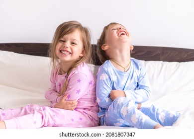 Two Preschool Toddler Children Siblings Boy And Girl Smiling Look At Side In Pink Blue Pajamas On White Bed. Little Baby Twins Have Fun. Happy Kids On Quarantine At Home. Friendship, Family Concept - Powered by Shutterstock