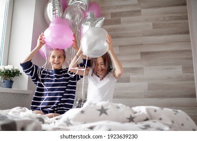 Two Preteen Sisters Twins Celebrate Birthday Day At The Morning, Active Kids Dressed In Pajamas Have Fun In The Bed With Balloons 