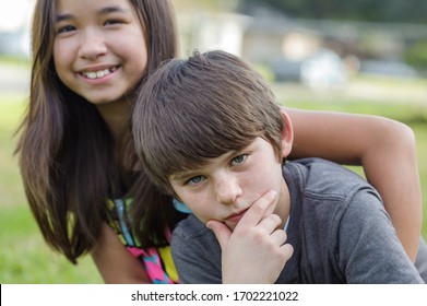 Two Pre-teens, Family Members Of Different Ethnicities, Being Silly, The Young Handsome Male Is In Focus While The Asian Female Is In The Bokeh Background, Shot Outdoors In South Louisiana.