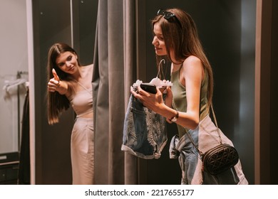 Two Pretty Best Friends Standing In The Changeing Room. One Of The Showing The Shorts The Other One Liking Them