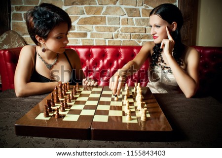 Two pretty girl-friends friends playing chess