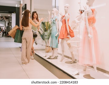 Two pretty girls looking at the shop window at the  mall - Shutterstock ID 2208414183