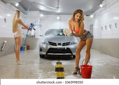 Two Pretty Girls Are Sexually Washing The Car With Sponges And Soap In A Car Wash Room