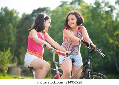 Two Pretty Hispanic Children Riding On Their Bikes