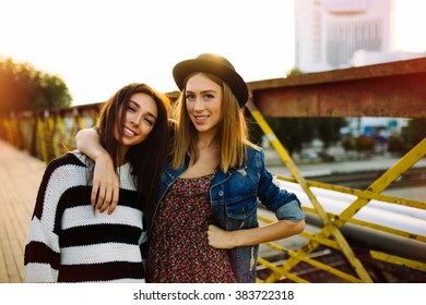 Two pretty sisters hipster girls hugs and having fun together, wearing trendy clothes, positive emotions, bright colors
