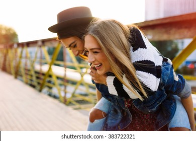 Two pretty sisters hipster girls hugs and having fun together, wearing trendy clothes, positive emotions, bright colors - Shutterstock ID 383722321