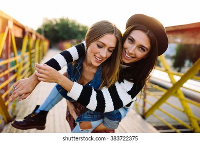 Two pretty sisters hipster girls hugs and having fun together, wearing trendy clothes, positive emotions, bright colors