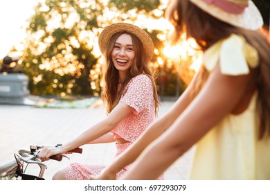 Two pretty smiling girls on a bicycle ride together outdoors